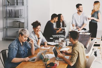 A diverse group of employees leveraging the benefits of workplace technology in the office